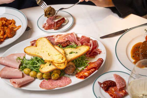 Two people sharing an antipasti plate on a table