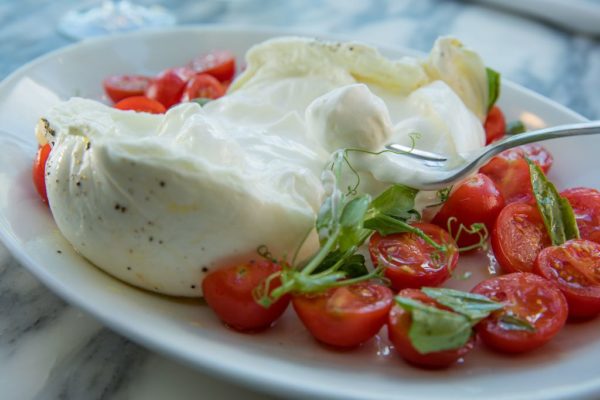 Burrata cheese and tomatoes served on a plate